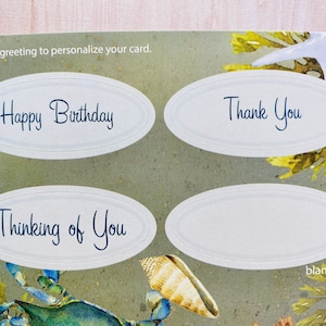 May include: Four oval-shaped greeting card stickers with a white background and blue text. The stickers have the following text: "Happy Birthday", "Thinking of You", "Thank You", and "blank".
