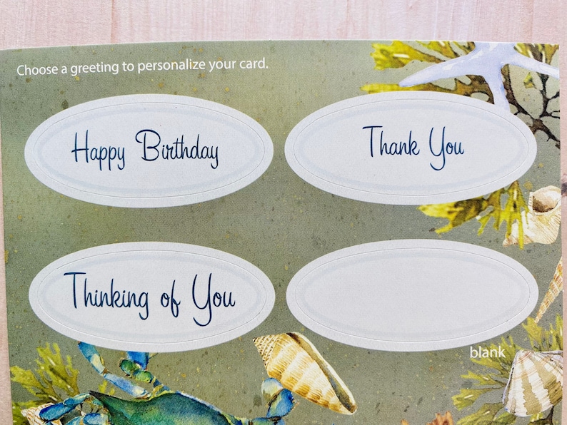 May include: Four oval-shaped greeting card stickers with a white background and blue text. The stickers have the following text: "Happy Birthday", "Thinking of You", "Thank You", and "blank".