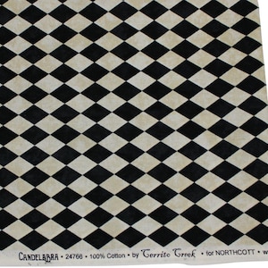 May include: A piece of fabric featuring a repeating black and cream diamond pattern. The bottom edge displays printed text reading: CANDELABRA 24766 100% Cotton by Cerrito Creek for NORTHCOTT. The material has a consistent geometric harlequin design.