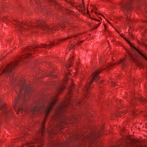 May include: A piece of fabric featuring a deep red and crimson color palette with a mottled, brushstroke-like pattern. The material displays soft folds and creases, creating a textured appearance with varying shades of dark and light red throughout.