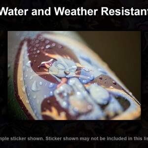 May include: A close-up of a sticker featuring a cartoon character. The sticker is covered in water droplets, demonstrating its water and weather resistance.