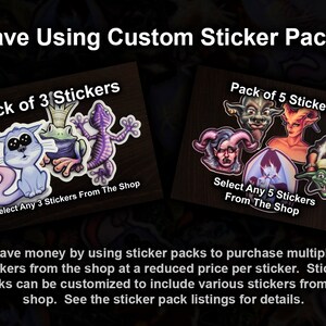 May include: Two sticker packs with different designs. The first pack has a cat, frog, and lizard. The second pack has a demon, a goblin, and a vampire. The text on the packs says "Pack of 3 Stickers" and "Pack of 5 Stickers".