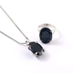 May include: A silver necklace and ring set with black oval-shaped gemstones. The necklace has a delicate chain and the ring has a simple band.
