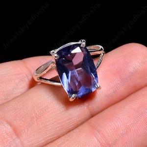 May include: A silver ring with a large, faceted, dark purple gemstone. The ring has a simple, elegant design.