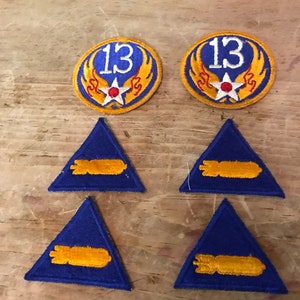 May include: Two round, yellow and red patches with the number "13" and a star in the centre. Four blue triangular patches with a yellow bomb design.
