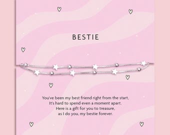 May include: A silver bracelet with star charms and small beads is displayed on a pink card. The word "BESTIE" is at the top, with a message below. The card has heart illustrations.