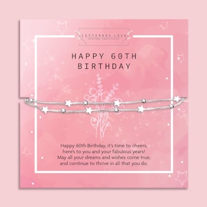 May include: A silver-toned double-strand bracelet featuring small star and bead charms, presented on a pink card with the text Happy 60th Birthday, Letterbox Love, and a printed message celebrating 60 years with wishes for dreams to come true.
