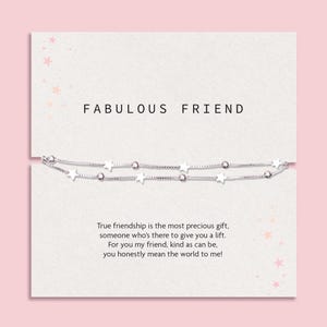 May include: A silver-toned double-strand bracelet featuring alternating small star charms and round beads, presented on a white card printed with the text FABULOUS FRIEND and a poem about friendship, decorated with small pink star illustrations.