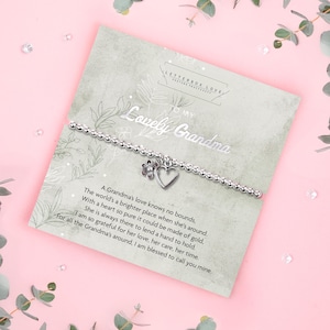 Silver beaded bracelet with heart and flower charms presented on a “To My Lovely Grandma” poem card, displayed in soft pink and green tones. A sentimental silver bracelet gift for Grandma or Nan, perfect for birthdays, Christmas, or family occasions.