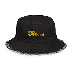 May include: Black denim bucket hat with a frayed edge and a gold embroidered eye and the word "Africa".