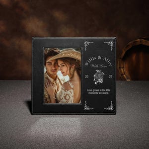 Könnte beinhalten: Schwarzer Leder-Bilderrahmen mit einem Foto eines Paares. Der Rahmen hat weiße Nähte und dekorative Eckakzente. Auf dem Rahmen steht "Willis & Alice With Love" und "Love grows in the little moments we share."
