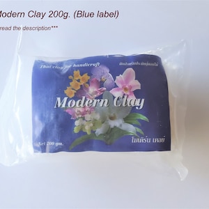 May include: A blue package of Thai Modern Clay for handicraft, with a label featuring orchids and the text "Modern Clay" in English and Thai. The package contains 200 grams of clay.
