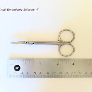 May include: Small embroidery scissors, approximately 10 cm long, with a silver finish. The scissors have a pointed tip and rounded finger holes. The text "Small Embroidery Scissors, 4" is visible in the image.