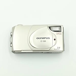 May include: A silver Olympus C-120 digital camera with a 2.0 megapixel resolution. The camera has a built-in flash and a Camedia logo.