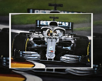 May include: A black and silver Formula 1 race car with the Petronas logo on the side. The car is on a race track with green grass in the background.