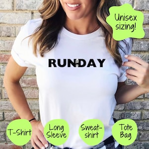 May include: White t-shirt with the word "RUNDAY" in black block letters. The "U" in "RUNDAY" is replaced with a shoe graphic. The shirt is labeled as available in T-shirt, Long Sleeve, Sweatshirt, and Tote Bag options. The shirt is described as having unisex sizing.