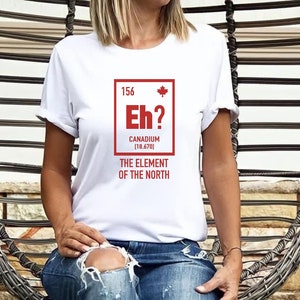 May include: White t-shirt with a red graphic of a periodic table element called "Canadium" with the symbol "Eh?" and the atomic number 156. The text below the element box reads "The Element of the North".