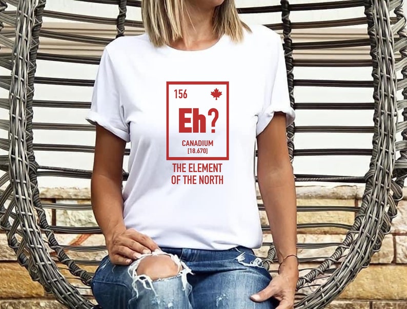 May include: White t-shirt with a red graphic of a periodic table element called "Canadium" with the symbol "Eh?" and the atomic number 156. The text below the element box reads "The Element of the North".