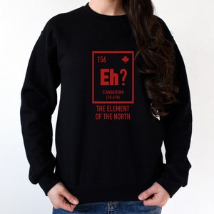 May include: Black sweatshirt with a red graphic of a periodic table element called "Canadium" with the symbol "Eh?" and the atomic number 156. The text below the element box reads "The Element of the North".