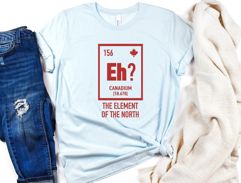 May include: Light blue t-shirt with a red graphic of a periodic table element. The element is labeled "Eh?" with the text "Canadium [18.670]" and "The Element of the North".