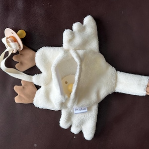 May include: White plush goose toy with brown felt wings and feet. The goose has a pacifier holder and a tag that says "Hey, Kido".
