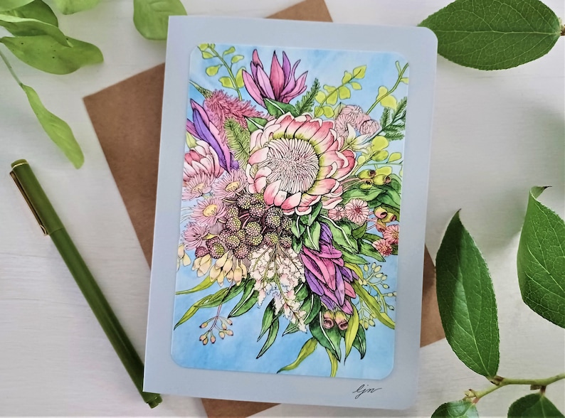 May include: A greeting card featuring a watercolor illustration of a bouquet of pink, purple, and green flowers on a light blue background. The card is signed "Gina".