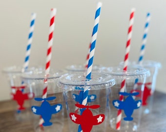 May include: Six clear plastic cups with red and blue striped straws. Each cup has a red or blue airplane sticker with white stars.