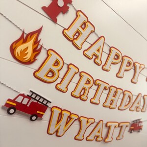 May include: A red, white, and yellow paper banner with the words "Happy Birthday Wyatt" and fire truck and fire hydrant cutouts.