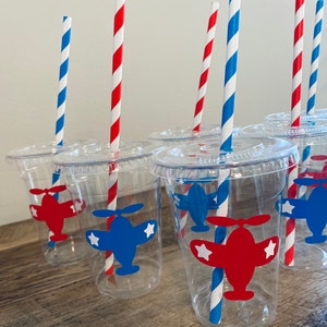May include: Clear plastic cups with red and blue airplane designs and red and blue striped straws.