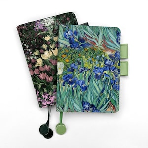 May include: Two rectangular notebook covers featuring artistic floral prints. One cover displays a dark garden scene with pink and yellow flowers, while the other depicts blue irises with green leaves. Both include attached ribbon bookmarks and pen loops.