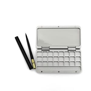 May include: A silver-colored metal watercolor palette box with twenty-four empty rectangular paint wells and a mixing area, accompanied by a black-handled paintbrush with a gold-colored ferrule and a matching black protective cap.