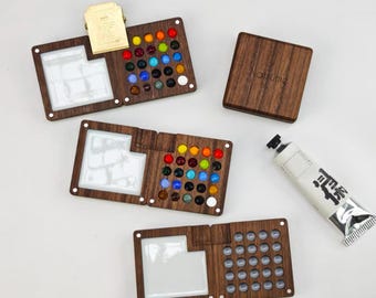 May include: Wooden art palettes with colorful glass beads and white paint wells. A tube of paint with Japanese text is next to the palettes. A small wooden box with the word "Natsume" is also in the image.