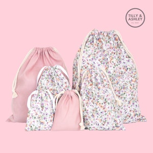 May include: Set of six drawstring bags in pink and floral print. The bags are made of cotton and have a natural cotton drawstring. The bags are perfect for storing small items, such as jewelry, cosmetics, or craft supplies.