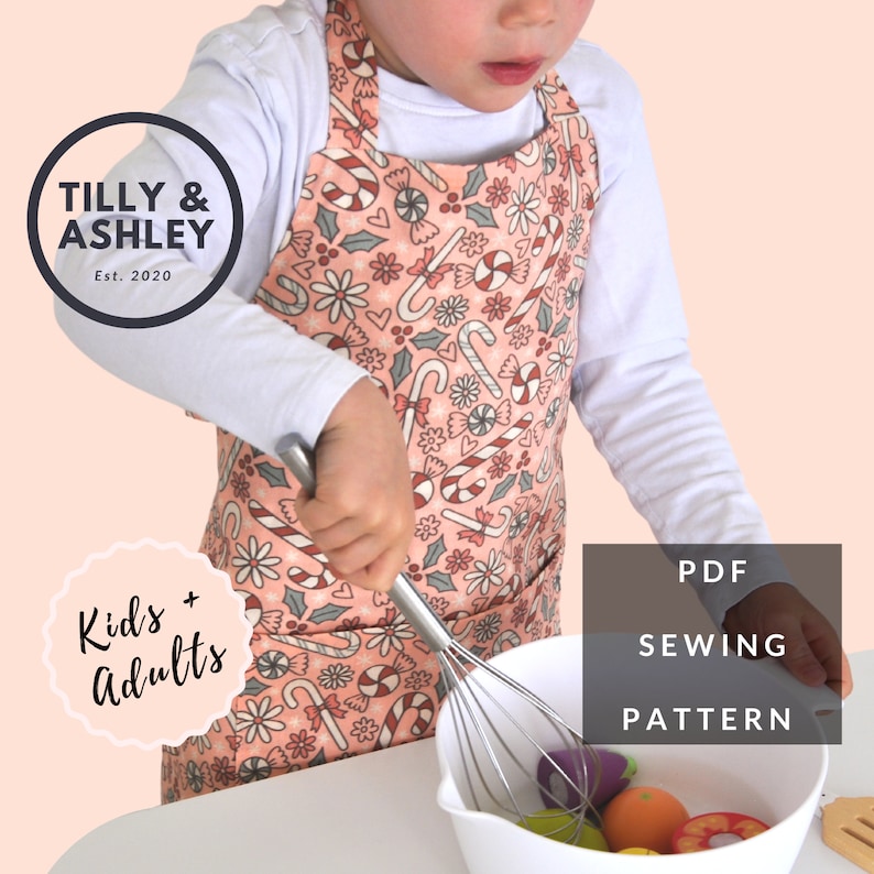 May include: A child wearing a pink and white candy cane and holly print apron with a pocket. The apron is for kids and adults. The text "Kids + Adults" is in a circle on the left side of the image. The text "PDF SEWING PATTERN" is in a rectangle on the right side of the image.