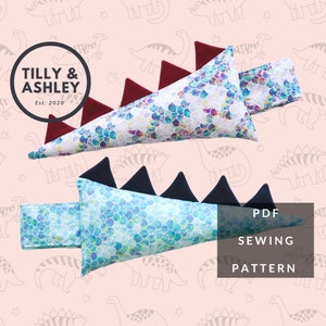 May include: PDF sewing pattern for a dinosaur tail cushion. The tail is made of two pieces of fabric with a scale pattern, one in blue and one in red. The pattern includes the text "PDF SEWING PATTERN".