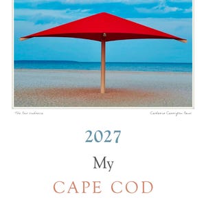 Peut inclure: Une couverture de calendrier avec une photographie d'un parasol de plage carré rouge vif sur une rive sablonneuse face à l'océan et au ciel bleu. Le texte indique 2027 My CAPE COD, Catherine Carrington Rand et RMS. Titre : The Red Umbrella.