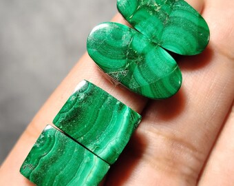 May include: Four green malachite gemstone cabochons, two oval and two square, with a swirling pattern.