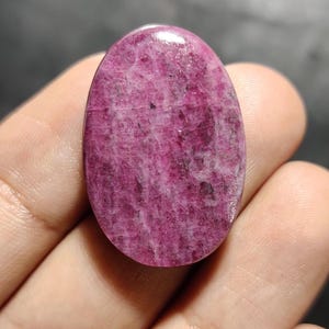 Könnte beinhalten: Ein rosa ovaler Cabochon-Edelstein mit marmoriertem Muster.