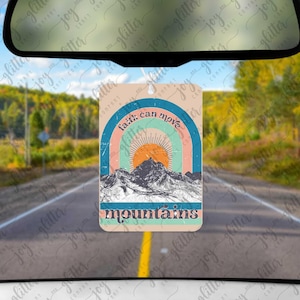 May include: A rectangular car air freshener hanging from a rearview mirror, featuring a graphic of a mountain range under a sun and rainbow arches. The text "faith can move" is arched above the sun, and "mountains" is printed in dark blue below.