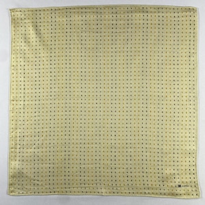 Peut inclure: Un carré de mouchoir jaune clair avec un motif répétitif de petits carrés marron foncé et dorés espacés uniformément. Le tissu a un léger éclat. Un petit logo est imprimé dans le coin inférieur droit.