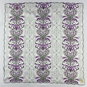 Könnte beinhalten: Quadratisches weißes Taschentuch mit einem sich wiederholenden Blumenmuster in Lila, Grün und Schwarz. Das Design zeigt vertikale Säulen aus stilisierten Blumen und Blättern vor einem grauen Hintergrund mit einem geschwungenen schwarzen Rand.