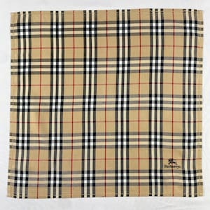 Peut inclure: Mouchoir carré à carreaux beiges, rouges, noirs et blancs, avec le logo Burberrys en bas à droite. Le motif à carreaux est un élément de design emblématique.