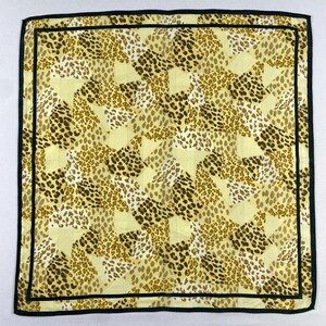 Peut inclure: Foulard carré avec un motif léopard dans les tons marron, beige et crème. Le foulard a une bordure noire et un design géométrique. Le foulard est fait d'une matière légère.