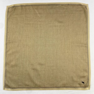 May include: A square tan handkerchief with a repeating dot pattern and a dark border. A small black logo is in the lower right corner. The handkerchief is made of a smooth material, possibly silk.