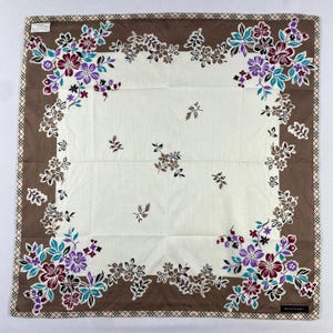 Peut inclure: Foulard carré à motifs floraux avec un centre blanc et une bordure marron. Le foulard présente un motif floral répété dans les tons de violet, sarcelle et marron. La bordure a un motif à carreaux et la marque "Burberry" est visible.