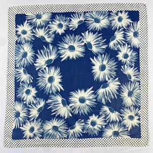 Peut inclure: Foulard carré à motifs floraux bleus et blancs. Le motif central présente des marguerites blanches sur fond bleu foncé. La bordure est blanche avec des pois noirs.