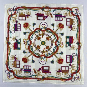 May include: Square white scarf featuring a repeating pattern of horse-drawn carriages in purple, teal, and gold. The scarf has a red and gold border with floral and chain details. The brand name "CELINE" is visible in the bottom right corner.