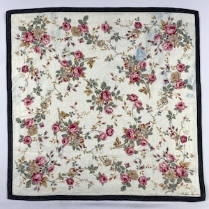 May include: Square, off-white floral scarf with a dark grey border. The scarf features a repeating pattern of pink and burgundy roses with green leaves and brown stems. The lower right corner has the text "Ralph Lauren".