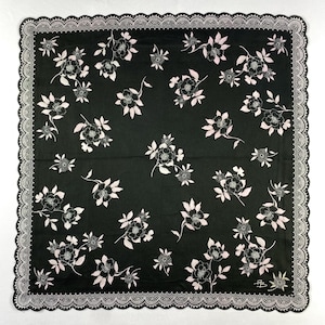 May include: Black square handkerchief with a white floral design and a white lace edge. The pattern includes stylized flowers and leaves. The handkerchief has a delicate, feminine appearance.