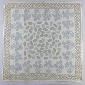Peut inclure: Carré de Sonia Rykiel blanc cassé avec un motif floral bleu clair et gris. Le motif présente des tulipes stylisées et une bordure géométrique. Le nom de la marque est visible en bas à droite.